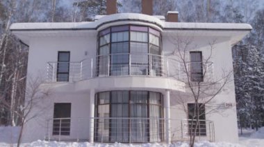 Güzel beyaz modern tasarım evi kışın karlı ağaçlarda ve açık mavi gökyüzü arka planında. Stok görüntüleri. İki katlı kır evi, mimari konsepti..