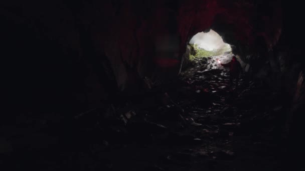 男人在黑暗而神秘的洞穴里移动，手里拿着一个红色的燃烧信号弹。 库存录像。 在洞穴中行走的男性探险家. — 图库视频影像