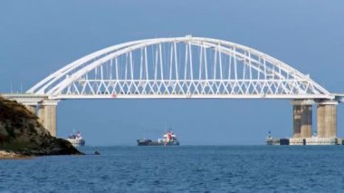 Büyük beyaz köprüsü olan güzel bir deniz manzarası, araba süren, ve güneşli bir yaz gününde köprünün altında yelken açan büyük bir gemi. Vuruldu. Köprünün arkasından geçen kargo gemileri, zaman aşımı..