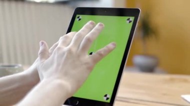 Yeşil ekranda tabletle çalışan bir adam. Stok görüntüleri. Yeşil tablet ekranına dokunarak ve bastırarak pürüzsüz elleri yakınlaştır