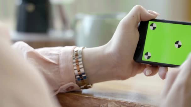 Primer plano de las manos femeninas sosteniendo el teléfono horizontal con pantalla verde. Imágenes de archivo. Freelancer femenina trabajando con el teléfono tocando en la pantalla verde — Vídeos de Stock