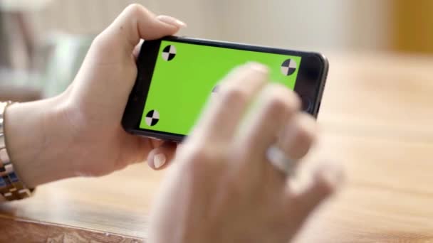 女性手牵着带绿色屏风的横向手机的特写。 库存录像。 在绿色屏幕上进行电话窃听的女自由职业者 — 图库视频影像