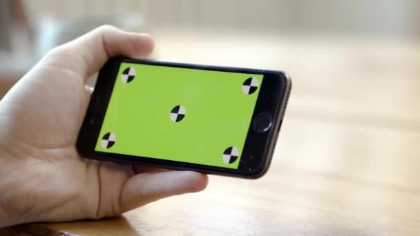 Närbild av hand hålla telefonen horisontellt med grön skärm. Lagerbilder. Person håller telefonen horisontellt med en hand för att titta på videor eller filmer — Stockvideo