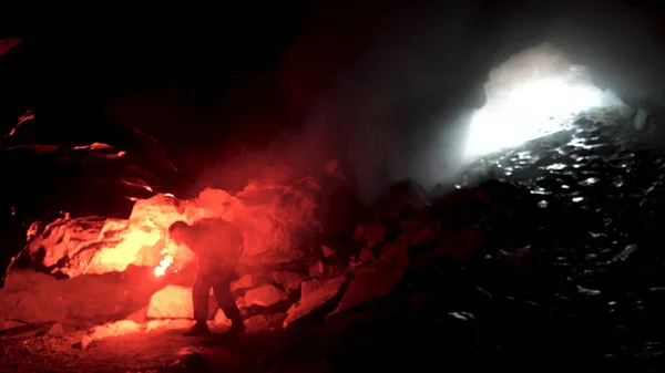 Homem geólogo com uma chama de sinal de queimadura vermelha explorando caverna escura subterrânea, conceito de ciência. Imagens de stock. Cientista tentando encontrar uma maneira de sair da caverna . — Fotografia de Stock