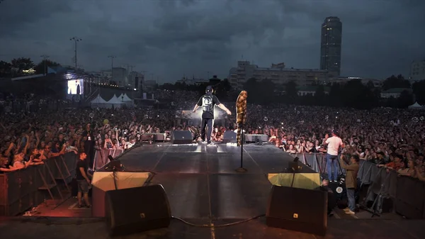 Russie - Ekaterinbourg, 09.12.2019 : La foule s'est rassemblée sur la place devant la scène avant le concert. L'action. Vue arrière d'un chanteur sur scène lors de sa perfomance . — Photo