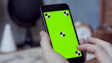 Evde cep telefonu kullanan bir adam. Stok görüntüleri. Bir adamın elinde yeşil ekran olan bir telefonu kapat.