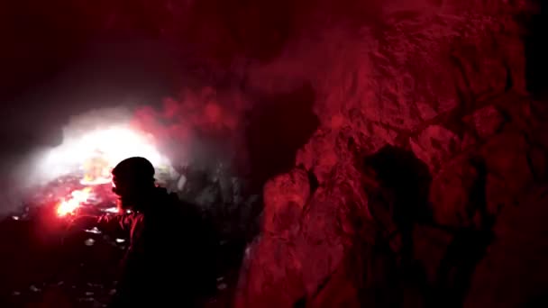 Uomo solitario con un segnale rosso ardente brillare in una caverna scura alla ricerca del buco, concetto di turismo. Filmati delle scorte. Maschio esplorare grotta sotterranea . — Video Stock