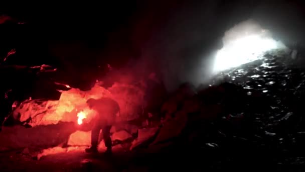 Homem geólogo com uma chama de sinal de queimadura vermelha explorando caverna escura subterrânea, conceito de ciência. Imagens de stock. Cientista tentando encontrar uma maneira de sair da caverna . — Vídeo de Stock