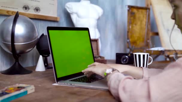 Jovem escrevendo um texto em seu laptop com tela verde. Imagens de stock. Jovem funcionária envolvida em trabalho criativo no laptop — Vídeo de Stock