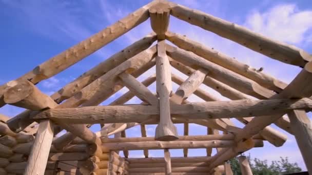 New home construction with wooden house frame on bright blue cloudy sky background, carpentry concept. Clip. Unfinished, ecological wooden house and building area.