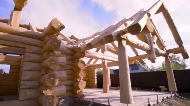 Facade of the residential wooden house construction in a sunny summer day. Clip. Wooden beams construction, building of the house in a village. — Stock Video