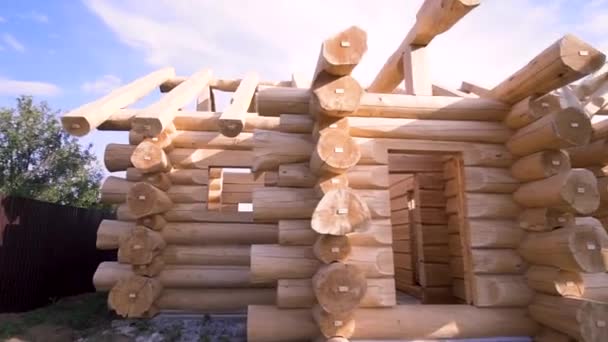 Facade of the residential wooden house construction in a sunny summer day. Clip. Wooden beams construction, building of the house in a village. — 비디오