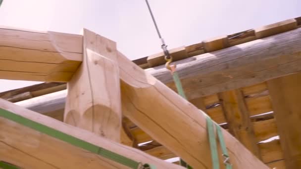 Bottom view of construction of eco-friendly house made of wood. Clip. The part of roof of the unfinished house from the log hanging on construction slings. — 비디오
