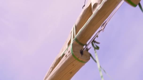 Elementos de construcción transportados por grúa sobre fondo azul del cielo. Clip. Elemento de techo de madera colgando de los eslingas de construcción . — Vídeos de Stock