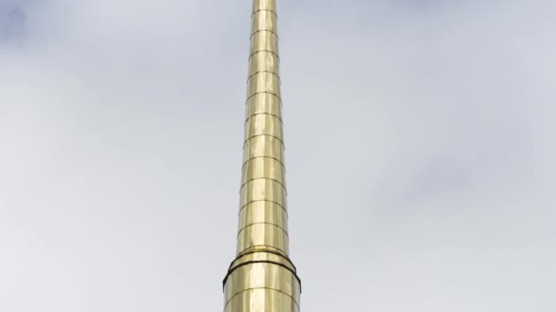 Goldener Kirchturm einer orthodoxen Kirche gegen den Himmel. Archivmaterial. Untere Ansicht einer langen, leuchtenden Turmspitze mit einem Kreuz eines Tempels oder einer Kathedrale, Religionskonzept. — Stockvideo