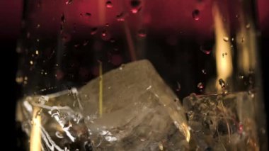 Koyu arka planda kırmızı loş ışık ile buzlu bardağa taze alkollü içecek dökmek. Stok görüntüleri. Kokteyl hazırlama sürecini kapat ve bardağa içecek ekle..