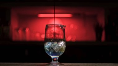 Bardağa taze alkollü içecek dökerken tezgahta buz küpleri vardı. Stok görüntüleri. Kokteyl hazırlama sürecini kapat ve bardağa mavi şurup ekle..