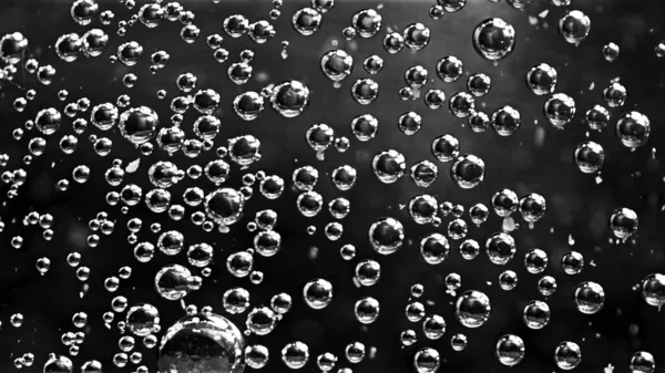 Burbujas de aire abstractas moviéndose bajo el agua. Imágenes de archivo. Primer plano de burbujas de oxígeno transparentes redondas que fluyen lentamente aisladas sobre fondo negro, monocromo . — Foto de Stock