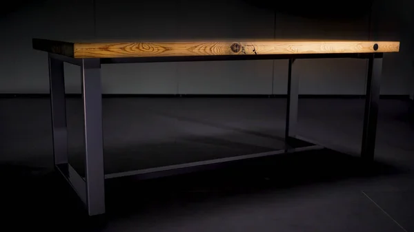 Drewniany stół ze stalowymi nogami na ciemnoszarym tle. Animacja. Abstrakcyjny stół z brązową drewnianą polerowaną powierzchnią stojącą w pomieszczeniu, w którym gaśnie światło. — Zdjęcie stockowe