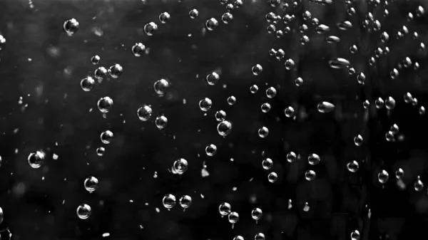 Abstract air bubbles moving underwater. Stock footage. Close up of round transparent oxygen bubbles flowing slowly isolated on black background, monochrome. — Stock Photo, Image