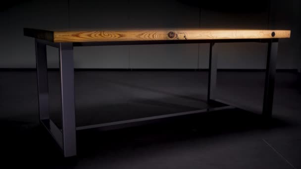 Fából készült asztal acéllábakkal, sötétszürke háttérrel. Animáció. Absztrakt asztal barna fa polírozott felülettel a szobában, ahol a fény ki van kapcsolva. — Stock videók