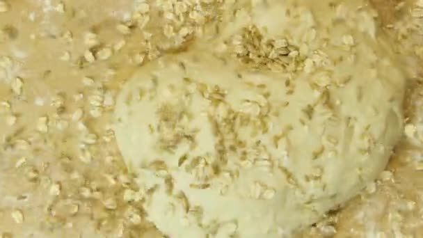 Top view of homemade dough with grains and flakes. Stock footage. Close up of cereal falling down on raw dough lying on wooden surface, cooking concept. — Stock Video