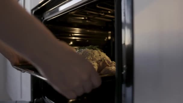 Cozinhe colocando frango cru com maionese branca no forno. Imagens de stock. Conceito de cozinha em casa, perto das mãos colocando frango com alecrim no forno . — Vídeo de Stock