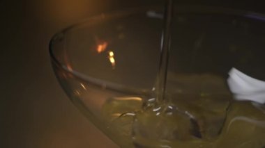 Martini bardağına buz küpüyle alkol dök. Stok görüntüleri. Kalın alkollü içecek koyu arkaplandaki şeffaf camlara dökülüyor..