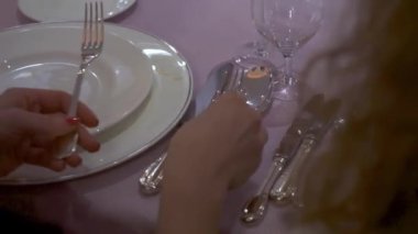 Tabakları, bardakları, gümüş takımları ve pembe masa örtüsü olan zarif yemek masası. Stok görüntüleri. Masayı hazırlayan kadın ellerinin kapatılması, görgü kuralları kavramı.
