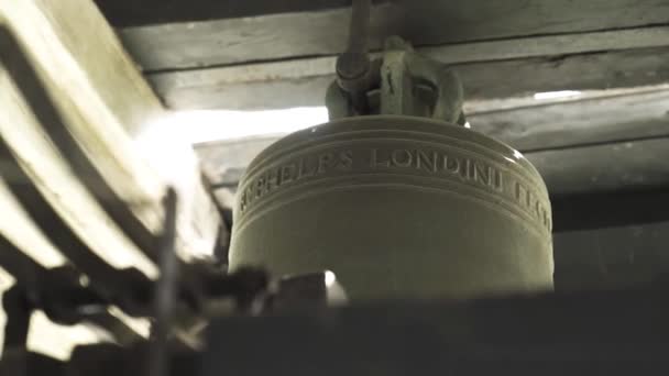 Botten utsikt över en stor kyrkklocka detaljer. Lagerbilder. Närbild av en gammal järnklocka på suddig bakgrund av trä barer, begreppet religion och historia. — Stockvideo