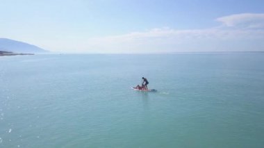 Kürekle birlikte yüzen bir çift. Şarjör. SUP-board 'daki deniz gezisi sırasında birkaç tatilcinin üst görüntüsü. Sörf yapan bir çiftle deniz manzarası