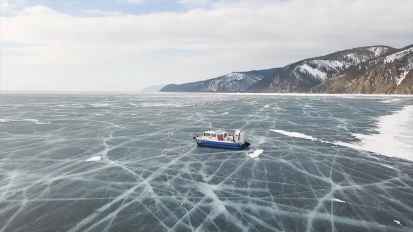 Grupo de personas de pie en el lago de hielo rajado cerca de aerodeslizador. Clip. La gente viaja y explora el lago congelado Baikal en un aerodeslizador seguro y cómodo . — Foto de Stock