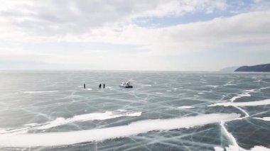 Hovercraft 'ın yanındaki buz gölünde duran bir grup insan. Şarjör. İnsanlar güvenli ve rahat bir hoverkraft ile donmuş Baykal Gölü 'nü gezip keşfediyorlar..