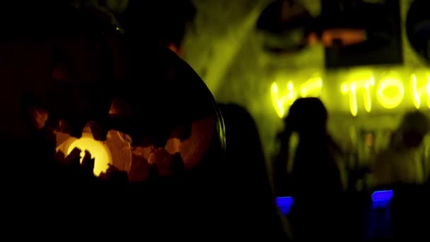 Halloween läskiga pumpor i den mörka baren. Lagerbilder. Närbild av skrämmande pampkin med en gul lampa inuti och människor som har roligt på bakgrunden. — Stockvideo