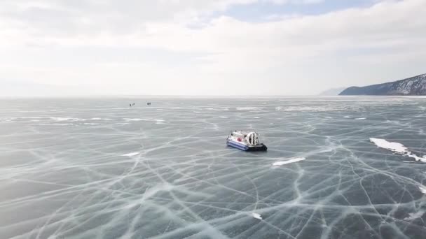 Groupe de personnes debout sur un lac de glace fissuré près d'aéroglisseurs. Clip. Les gens voyagent et explorent le lac Baïkal gelé dans un aéroglisseur sûr et confortable. — Video