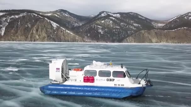 Zijaanzicht van bewegende hulpverleningsboot op bevroren meer. Een knip. Lucht uitzicht op de badmeester hovercraft glijden op de winter bevroren prachtige meer op een winterdag. — Stockvideo