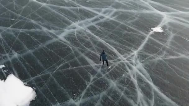Вид зверху на людину, що катається на ковзанах на відкритому повітрі на замерзлому водосховищі. Кліп. Чоловічі туристичні ковзани на замерзлому озері з густим льодом з глибокими тріщинами під ногами . — стокове відео