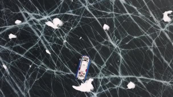 在贝加尔湖冰冻的冰面上的气垫船的空中俯瞰。剪断。冬季，气垫车停放在深暗湖面的冰上. — 图库视频影像
