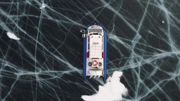 Вид зверху на рятувальний човен на замерзлому озері з товстим шаром прозорого тріснутого льоду. Кліп. Вид з повітря рятувального літака на зимове заморожене приголомшливе озеро в зимовий день . — стокове відео