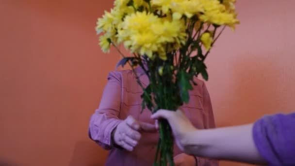 Äldre kvinnor får blommor. Begreppet. Födelsedag för äldre kvinna i skyddsmask under virusepidemin. Sjukdom eller är allergisk mot blommor — Stockvideo