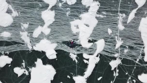 Vista aerea dall'alto del gruppo di persone si trovano su ghiaccio trasparente di spessore. Clip. Macchina fotografica in movimento verso amici felici sdraiati sul lago ghiacciato in una forma di cerchio. — Video Stock