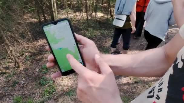 Trasa na mapě GPS v telefonu. Klip. Muž ukazuje cestu po telefonu na skupinovou túru v lese. Turistická trasa na mapě GPS v telefonu — Stock video