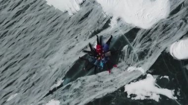 Bir grup insanın havadan görünüşü kalın şeffaf buz üzerinde yatar. Şarjör. Kamera, donmuş gölün üzerinde daire şeklinde duran mutlu arkadaşlara doğru hareket ediyor..