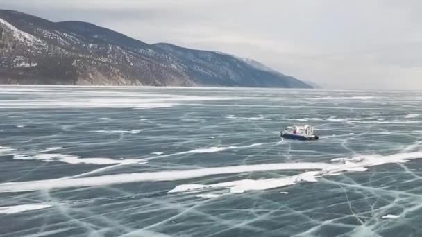 Vue aérienne du véhicule aéroglisseur typique lorsqu'il se déplace sur une surface de glace claire et fissurée. Clip. Lac Baïkal, Sibérie, Russie, transport maritime sur le lac gelé. — Video