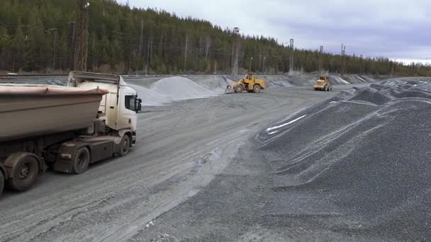 Enkaz yığınlarının yanında çalışan büyük ve güçlü bir makine. Hisse. Ormanın yakınındaki beton fabrikasının deposuna dev kaya yığınlarının yanına çöp kamyonu ve traktörler dökün.. — Stok video