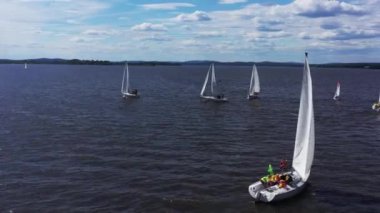 Birkaç güzel beyaz yat güzel gölet boyunca yüzüyor. Video kaydı. Mavi bulutlu arka plandaki yarışma sırasında nehirdeki küçük yelkenli teknelerinin hava görüntüsü.