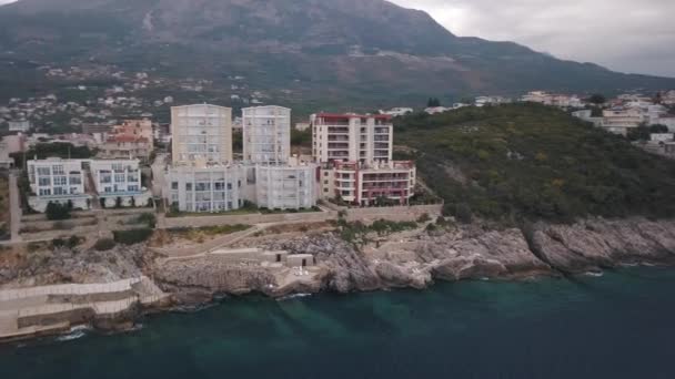 Vackra skogsklädda kullar som leder ner till kusten med den steniga stranden och azurhavet. Lager. Resor och semester koncept, antenn i en liten stad belägen vid havet och gröna berg. — Stockvideo