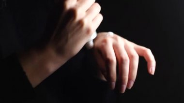 Ellerinin kurumasını önlemek için nemlendirici krem kullanan bir kadın. Kavram. Şefkatli kadın ellerini kapayarak siyah arka planda beyaz losyon sürüyor..