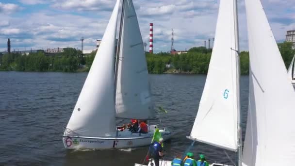 Egy csapat kis jacht vitorlázik a széles folyón egy napos nyári napon. Videó. A jachtklub tagjai jól érzik magukat, miközben a víztározón hajóznak át.. — Stock videók