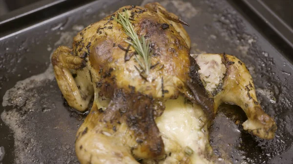 Nahaufnahme eines guten Hühnchens, das auf einer Backform mit einem Zweig Rosmarin gekocht wird. Handeln. Lecker zubereitetes Huhn mit knuspriger Kruste gefüllt mit Mayonnaise-Sauce. — Stockfoto